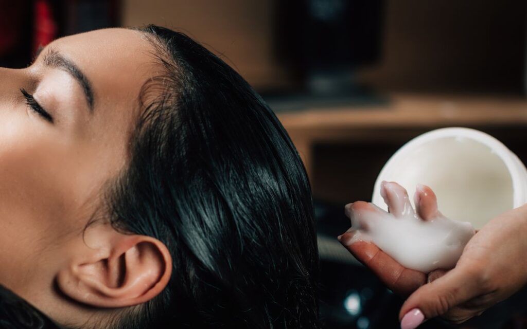 peluqueria aplica crema nutritiva en cabello de clienta